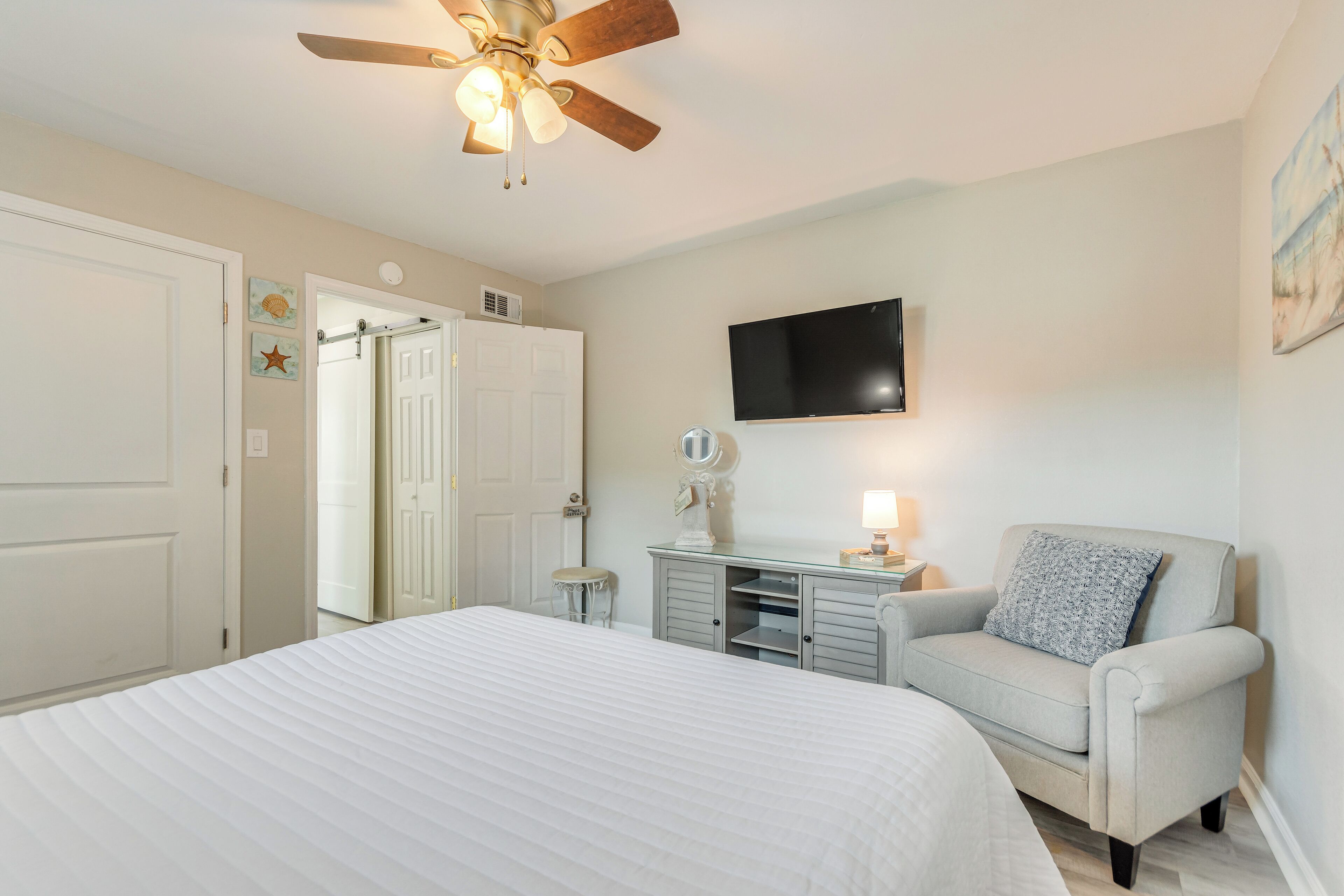 A bedroom with a bed, a vanity with a mirror, a chair, and a ceiling fan.