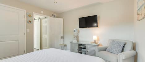 A bedroom with a bed, a vanity with a mirror, a chair, and a ceiling fan.
