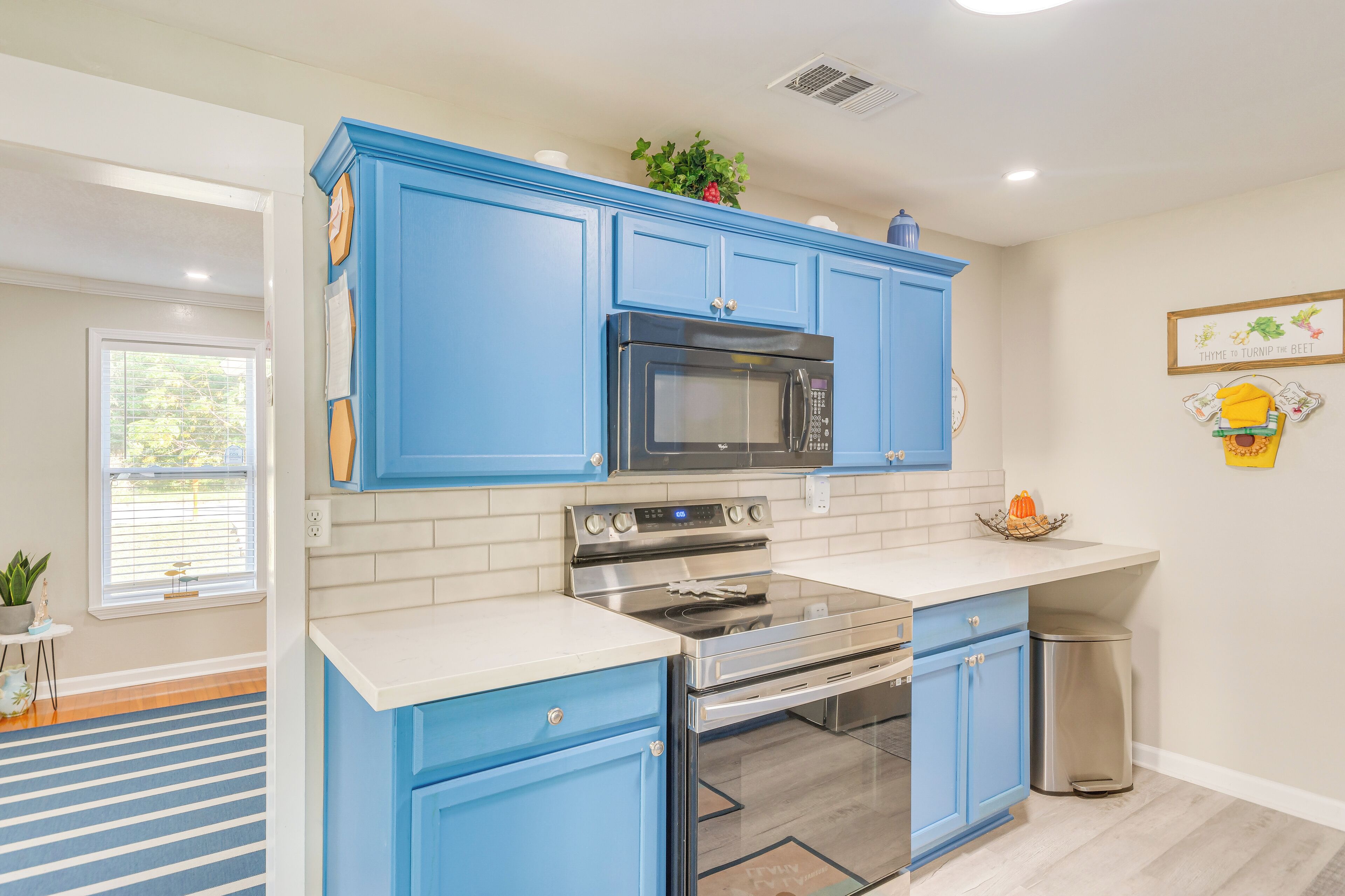 A modern kitchen with blue cabinets, stainless steel appliances, and a white countertop.