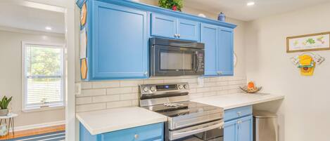 A modern kitchen with blue cabinets, stainless steel appliances, and a white countertop.