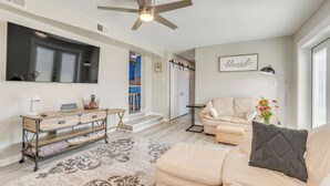 A spacious living room with a beige sofa, a coffee table, and a console table with a 'Welcome' sign. A ceiling fan and a floor lamp are visible. - 1 Mi to Dtwn: Home w/ Furnished Patio in Pensacola (Pensacola)