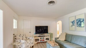 A living room with a television, a patterned armchair, a light blue sofa, and a small wooden coffee table. - 5 Mi to Vero Beach: Vintage Home w/ Sauna & Grill! (Vero Beach)