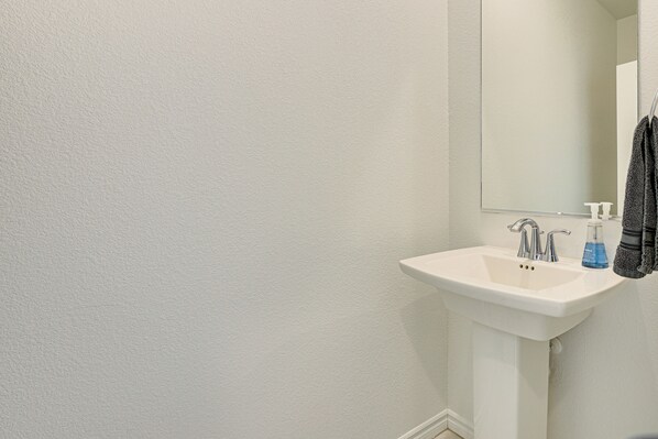 A bathroom with a white sink, a mirror, and a towel hanging on the wall.