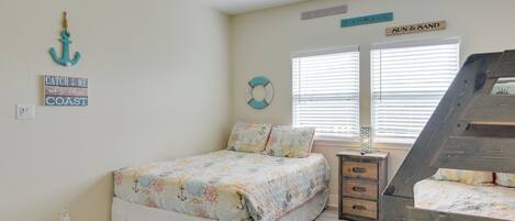 Un dormitorio con una cama, una mesita de noche, un banco de madera y un ventilador de techo.