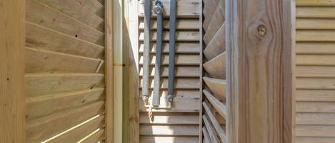 Un interior de madera con listones horizontales, una tubería visible y un marco de puerta.