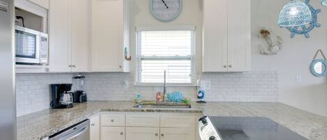 A kitchen with white cabinets, a microwave, a coffee maker, and a stove.
