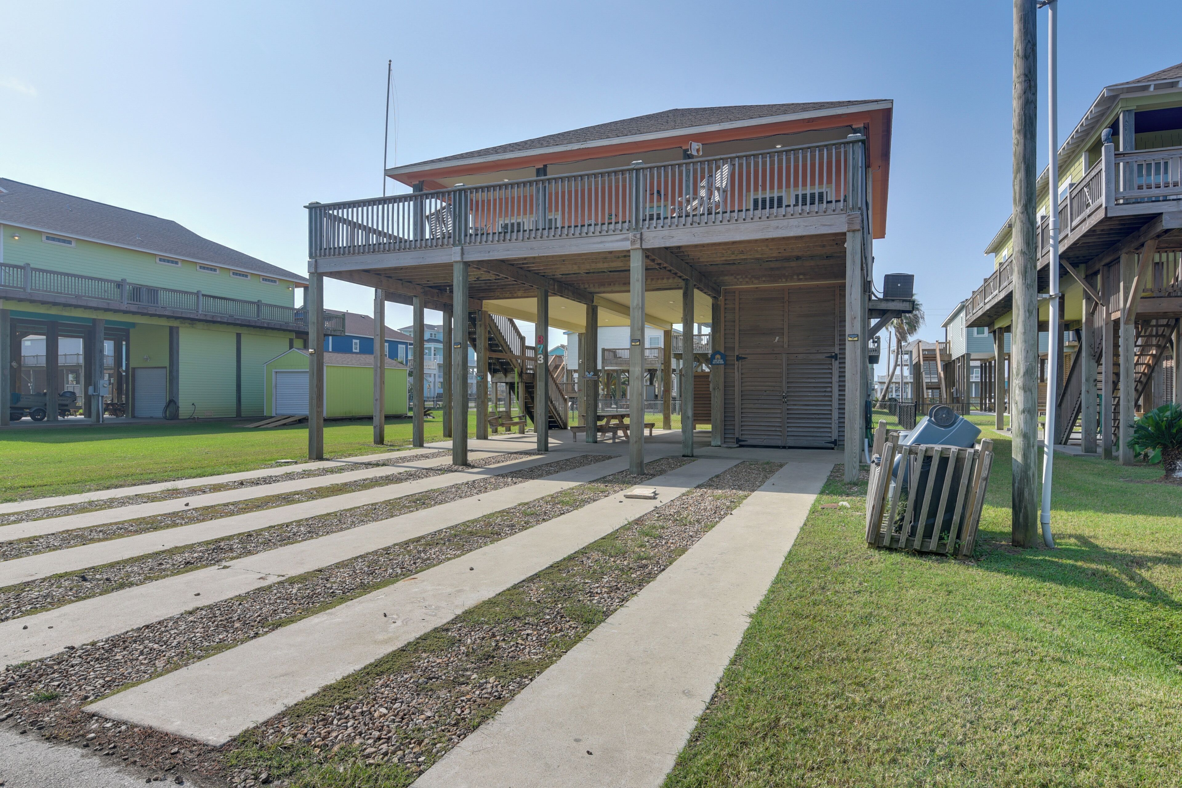 A building with a covered outdoor area, a staircase, and a trash bin.