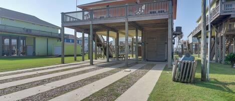 A building with a covered outdoor area, a staircase, and a trash bin.