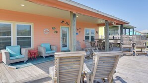 Een strandhuis met een overdekte patio, rieten meubels en een houten terras.