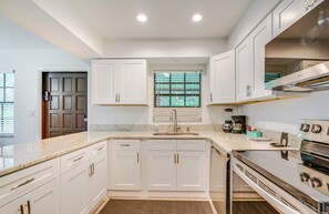 A modern kitchen with white cabinetry, a stainless steel oven, and a window with blinds. - 8 Mi to World Equestrian Center: Walkable Getaway (Ocala)