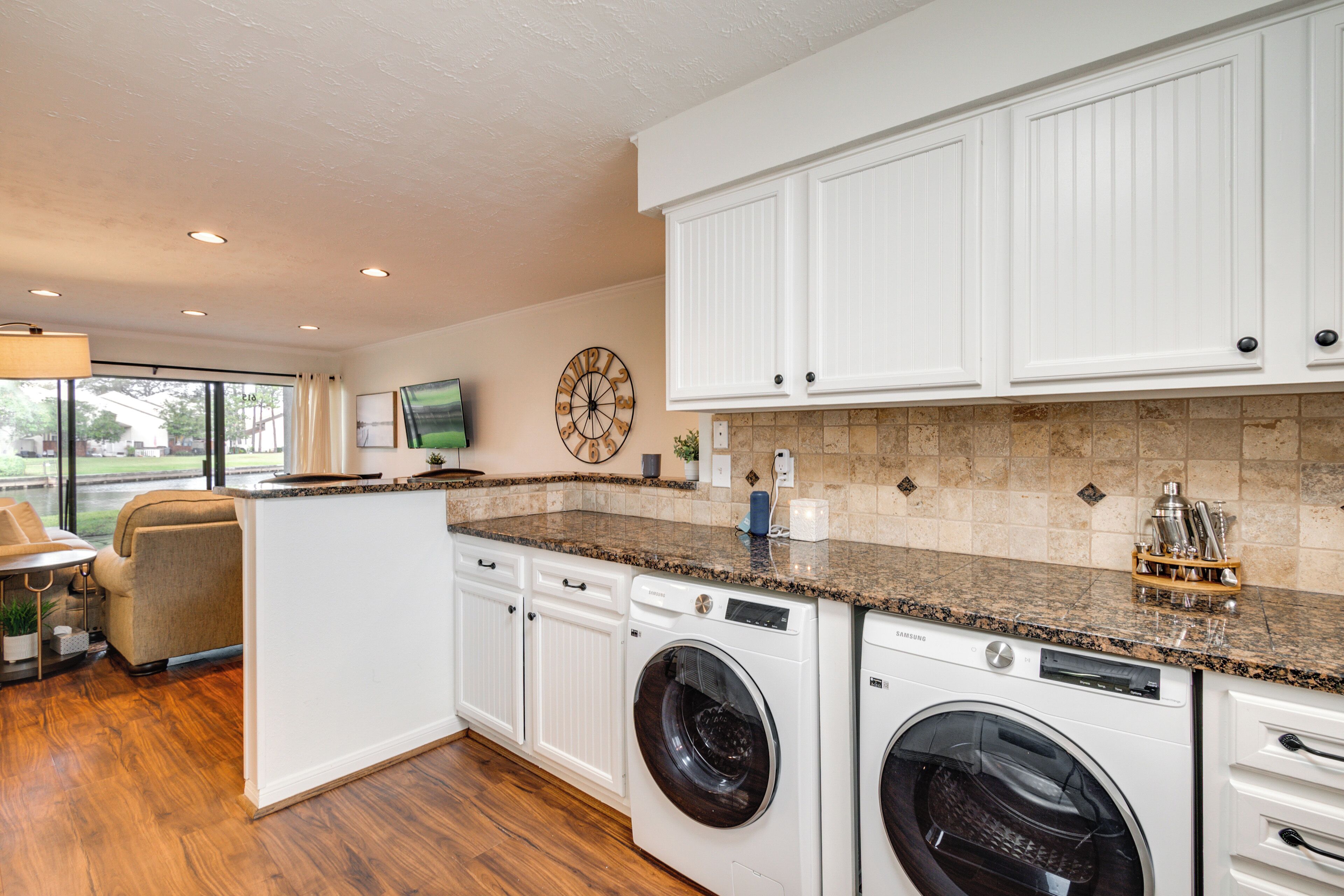 A modern kitchen with built-in appliances, white cabinetry, and a large window providing natural light.