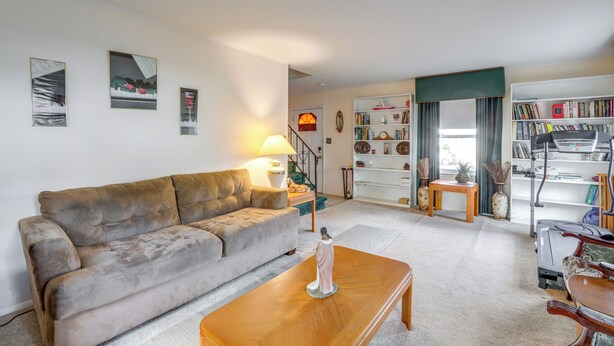 Ein Wohnzimmer mit Sofa, Couchtisch und Lampe. Eine Treppe führt in einen anderen Raum.