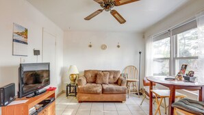 Ein Wohnzimmer mit Fernseher, Sofa und Esstisch.