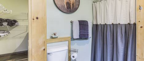 Une salle de bain équipée de toilettes, d’un porte-serviettes, d’un rideau de douche et d’un tableau représentant un taureau accroché au mur.