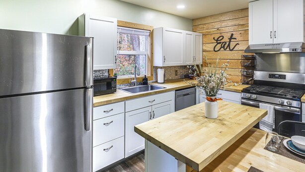 Una cocina moderna con electrodomésticos de acero inoxidable, armarios blancos y una pared de acento de madera.