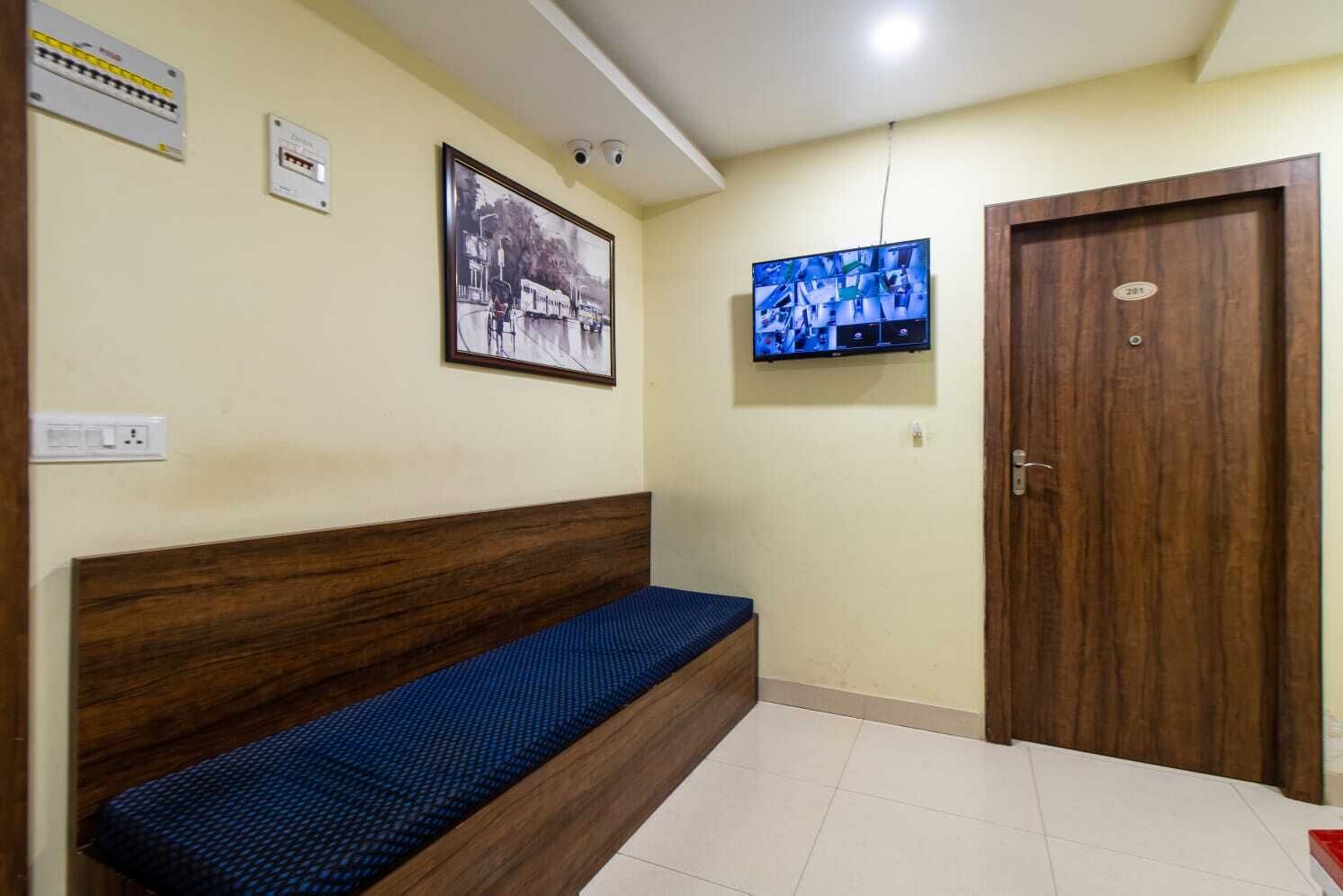 Une pièce avec un banc en bois, un téléviseur fixé au mur et une porte avec une plaque numérotée.