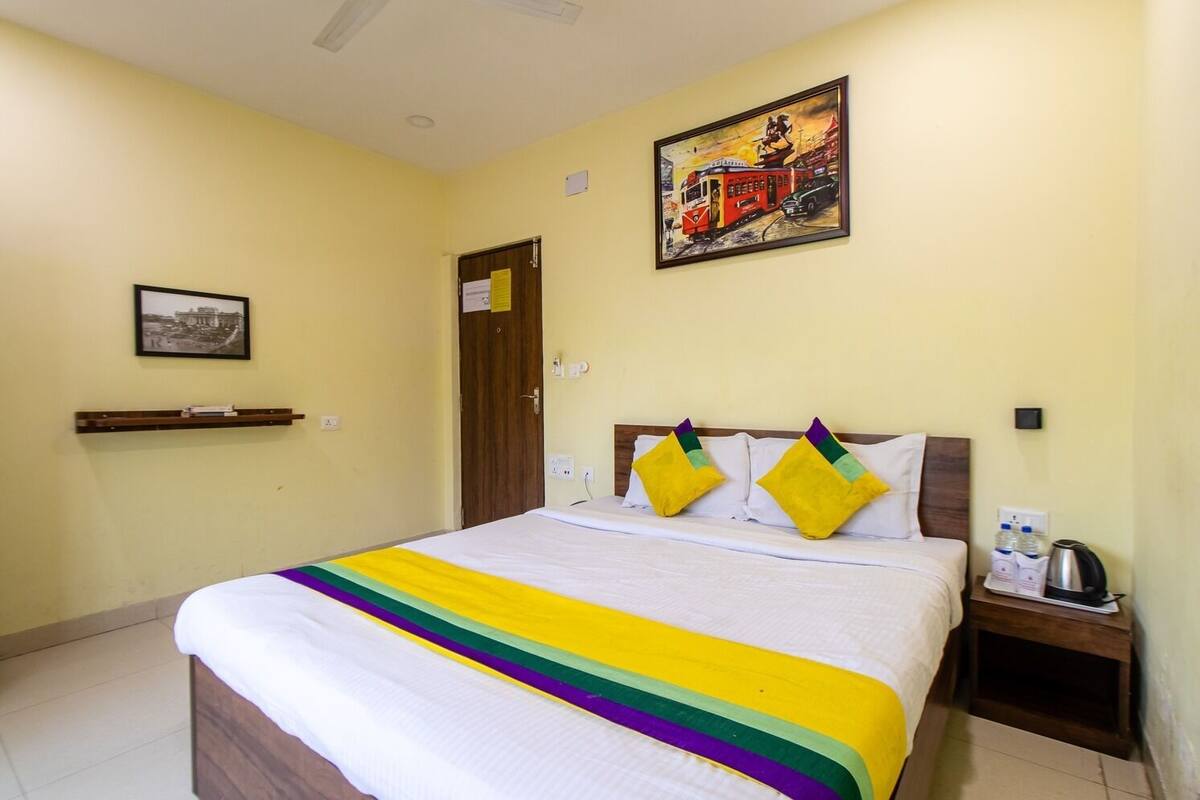 Una habitación de hotel con una cama, una mesita de noche, un cuadro y una puerta.