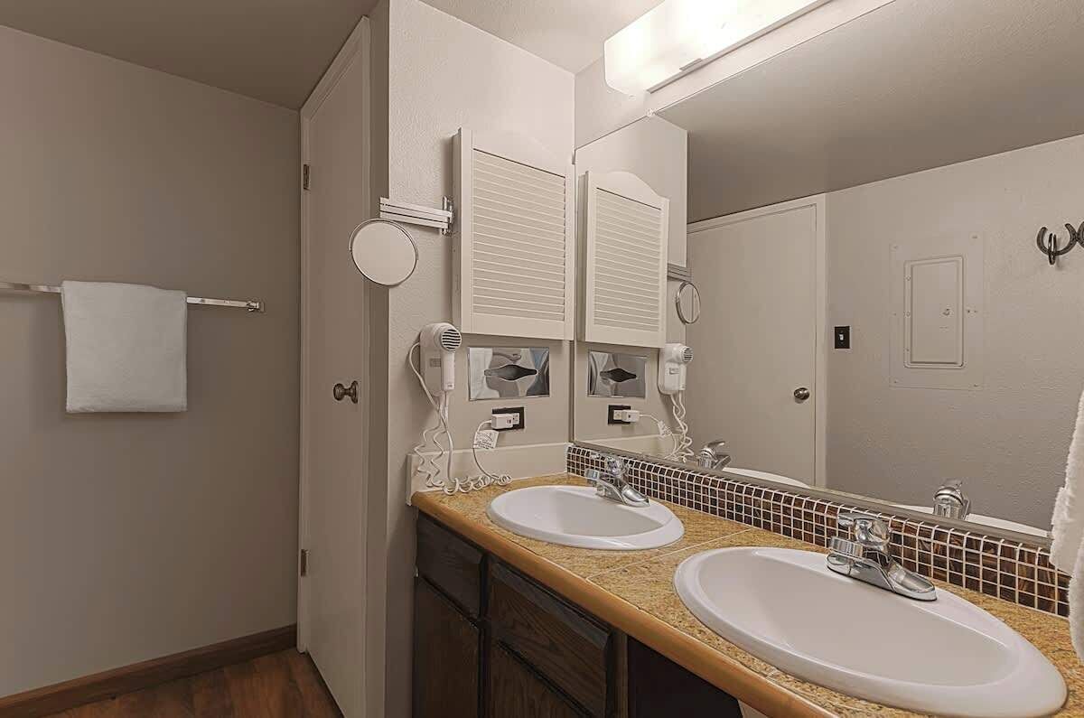 A bathroom with two sinks, a towel rack, and a mirror.