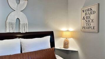 Een slaapkamer met een bed, een wandlamp en een motiverende quote op de muur.