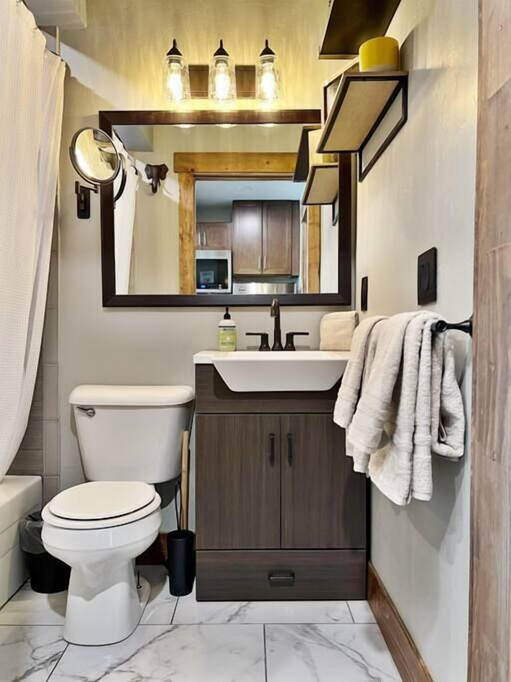 A compact bathroom with a toilet, sink, and mirror.