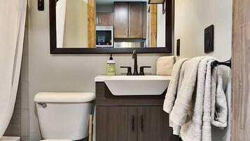 A compact bathroom with a toilet, sink, and mirror.