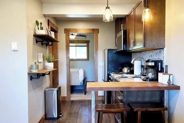 A compact kitchen with wooden cabinets, a built-in stove, and pendant lighting.