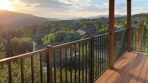 A wooden deck with a metal railing overlooking a residential area with houses and trees, under a clear sky. - Scenic Mountainside Studio (Steamboat Springs)