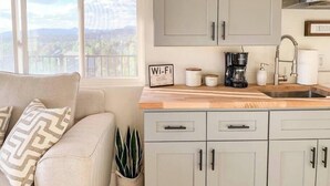 A modern kitchen with grey cabinets, a wooden countertop, and a view of mountains through a large window. - Scenic Mountainside Studio (Steamboat Springs)