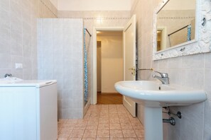 A bathroom with a white sink, a mirror, and a shower area. - 100 m² Downtown Apartment for Up to 8 Guests + Free Private Parking (Verona)