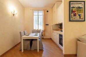 A dining area with a table and chairs, a window with curtains, a wall-mounted light fixture, and a painting on the wall. - 100 m² Downtown Apartment for Up to 8 Guests + Free Private Parking (Verona)