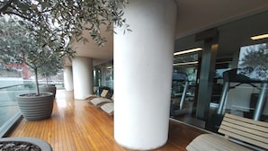 Un espace extérieur abrité, doté d’un plancher en bois, de grands bacs à plantes et de sièges.