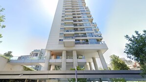 Un grand immeuble moderne, avec de nombreux balcons et un toit plat.