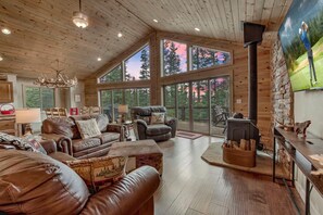 A spacious living room with leather furniture, large windows, and a fireplace.