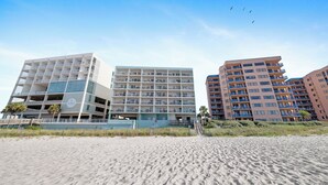 A beachfront hotel with multiple floors, balconies, and a clear view of the beach. - Emerald Skye 51 by Liquid Life (Orange Beach)
