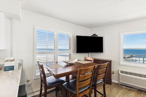 Una habitación con una mesa de comedor, sillas, un televisor de pantalla plana y vistas al océano.