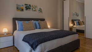 A bedroom with a bed, bedside tables, a mirror, and wall art. - Torino Modern Stay by Wonderful Italy (Torino)