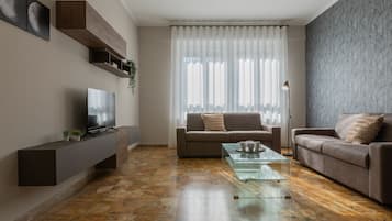 A modern living room with a sofa, a coffee table, a TV, and a patterned wall.