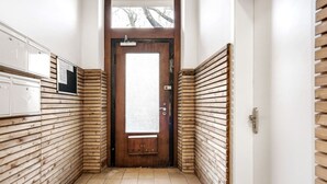Un couloir étroit aux murs recouverts de lambris en bois, avec un sol carrelé et une porte au fond.