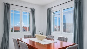 Ein Konferenzraum mit einem Holztisch, sechs grauen Stühlen und einer weißen Tischdecke.