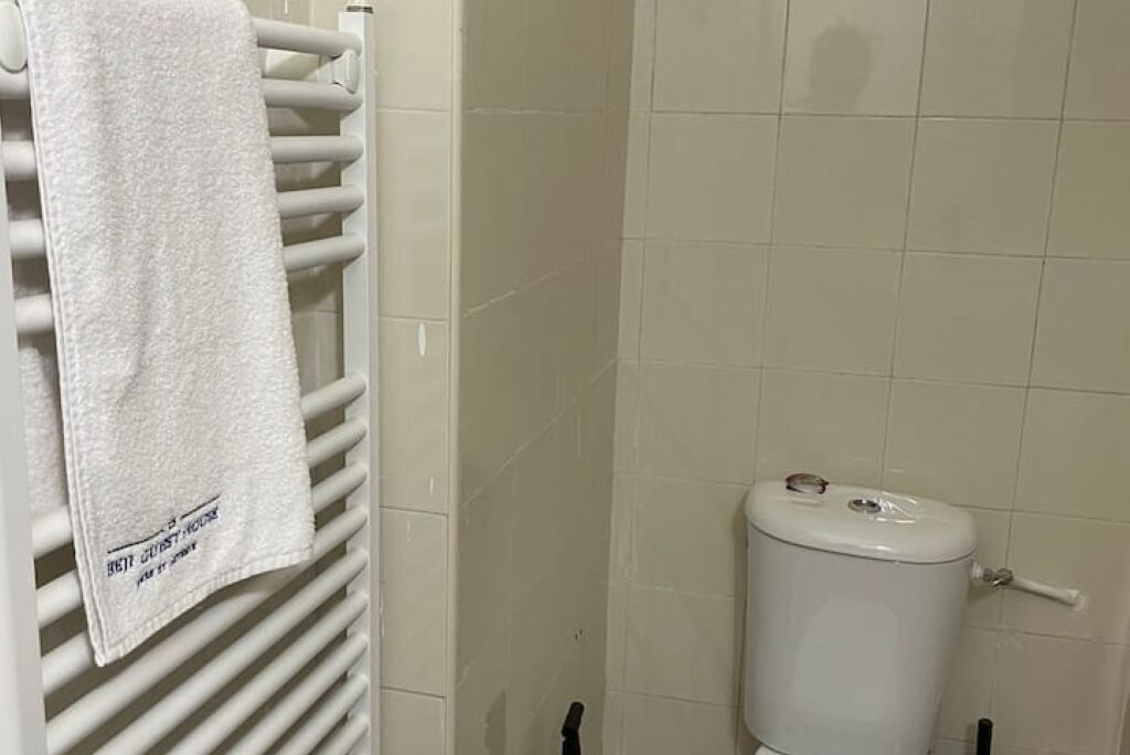 A bathroom with a white towel hanging on a radiator, a white toilet, and tiled walls.