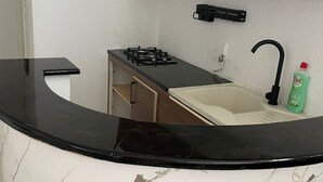 A compact kitchen with a gas stove, a sink, and a bottle of dish soap. - Serenity Home (La Marsa)