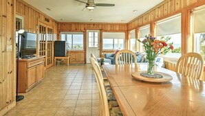 A spacious kitchen with wooden cabinets, a dining table with chairs, a TV, and a view of the ocean. - Bayfront in Broadkill Beach (Milton)