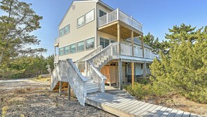 A two-story house with a wooden deck and a staircase leading to a balcony. - Bayfront in Broadkill Beach (Milton)