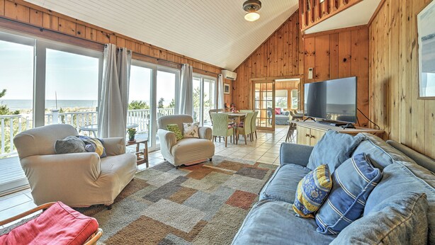 A spacious living area with a large TV, comfortable seating, and a view of the outdoors. - Bayfront in Broadkill Beach (Milton)