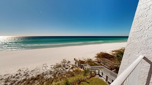 A beach view from a balcony with a clear sky, sandy beach, and wooden walkways. - Beach House 401d 1 Bedroom Condo (Miramar Beach)