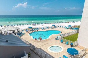 A pool area with a view of the beach and ocean.