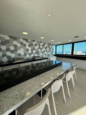A modern kitchen with a large island, bar stools, and a view of the city through large windows.