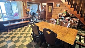 A cozy dining area with a checkered floor, wooden tables, and chairs. A staircase is visible in the background. - A Sense Of Place Limit 17 7 Bedroom Villa (Sebago)
