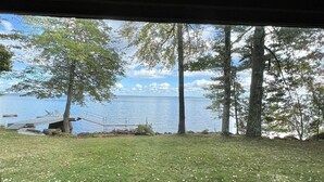 A view from inside a vehicle, looking out at a grassy area with trees and a body of water. - A Sense Of Place Limit 17 7 Bedroom Villa (Sebago)