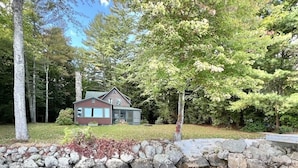 A cabin with a stone wall and a pond in front. - A Sense Of Place Limit 17 7 Bedroom Villa (Sebago)